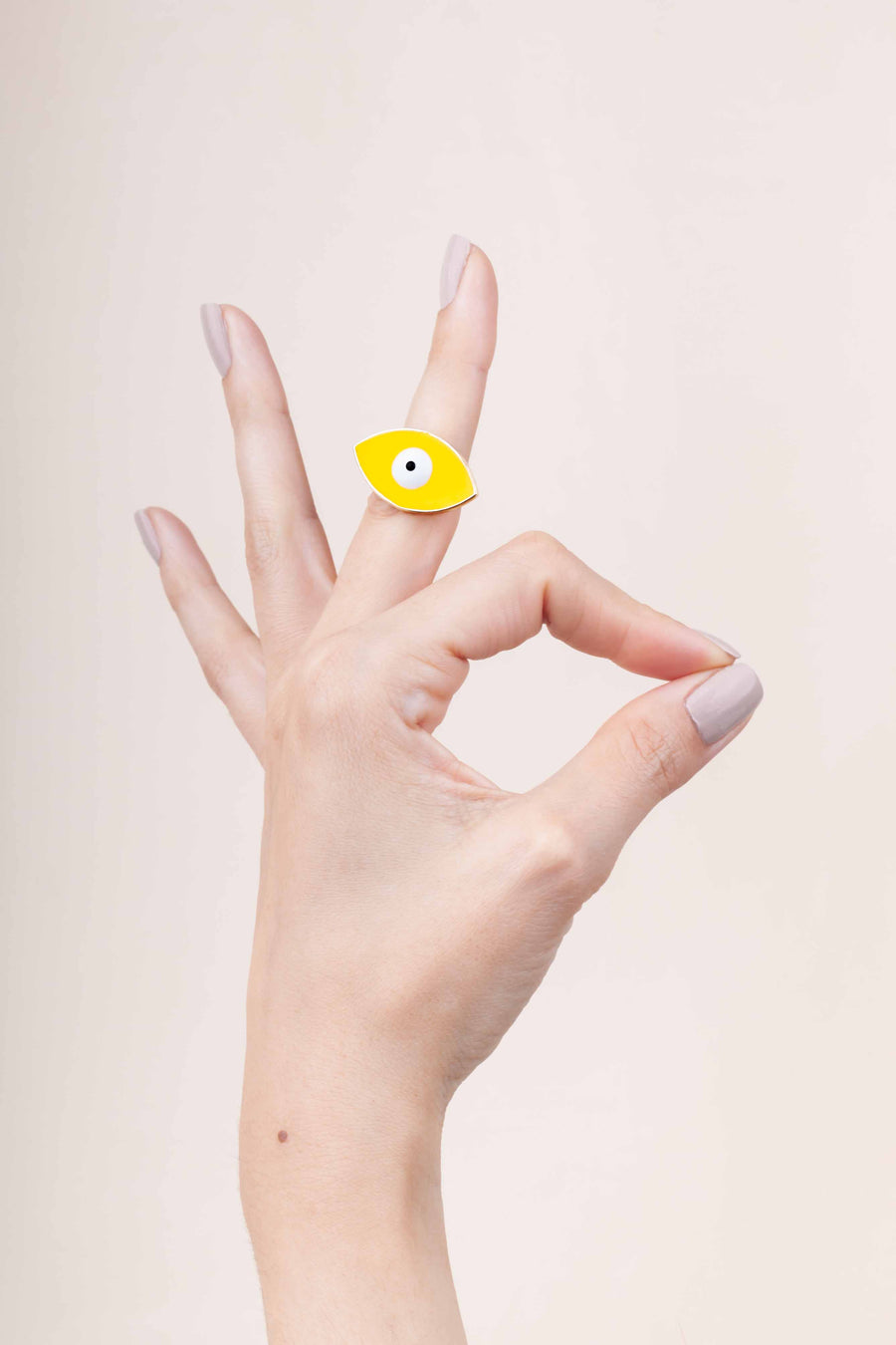 Hand painted enamel and gold plated yellow eye ring worn on finger